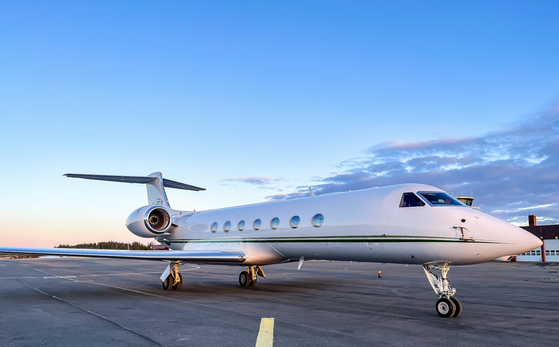 Real Gulfstream G550 private jet parked on an airport ramp at dusk