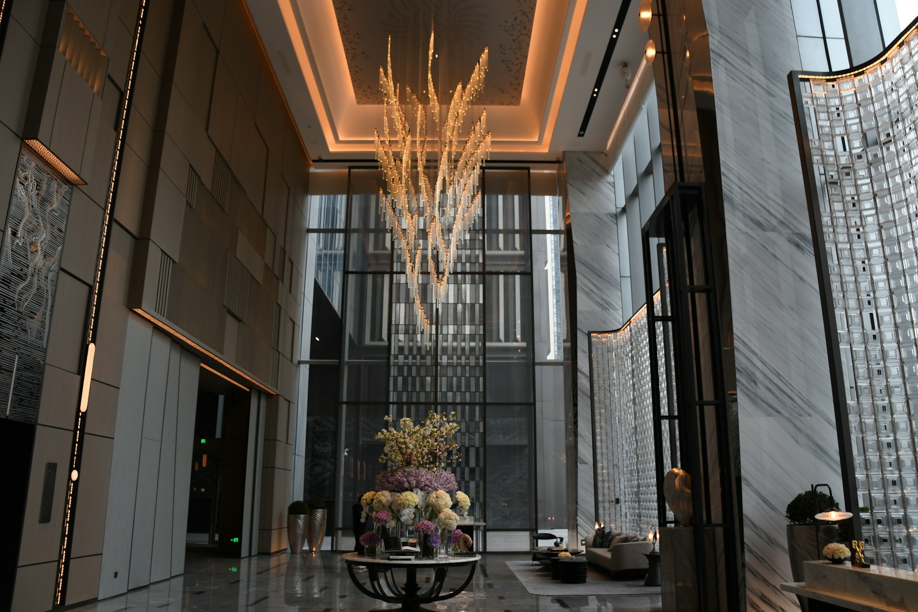 Luxury hotel reception area with marble floors, a chandelier, and flowers